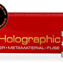 Red box packaging labeled 'Holographic' in gold with 'SR • METAMATERIAL • FUSE' text, plus two red cylindrical fuses, one larger, against a white background. A circular award badge overlaps the left corner stating 'Best Of 2026 Award' and 'Enjoy the Music' with a blue musical note.